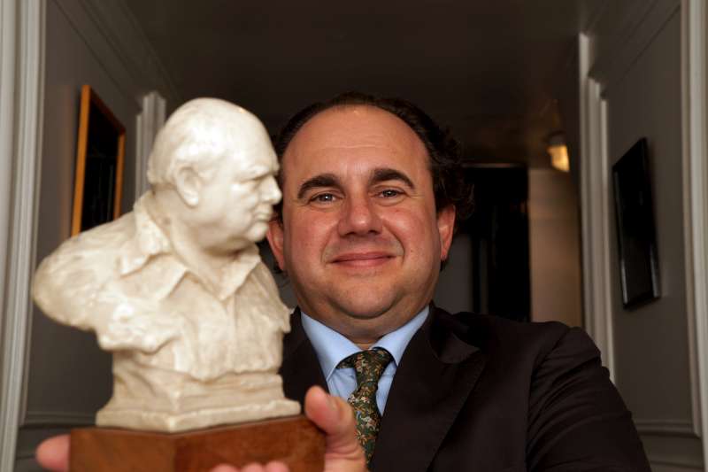Hubert de Billy - Pol Roger. Hubert de Billy stands with a bust of Winston Churchill, and therefore showing the portrait to be associated with Pol Roger as the top cuvée is Winston Churchill. For a further reference to Britain he is photographed in a "White hall".
